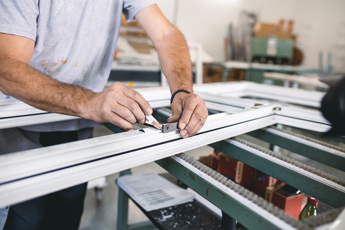 Manual worker assembling PVC doors and windows. Manufacturing jobs. Selective focus. Factory for aluminum and PVC windows and doors production.